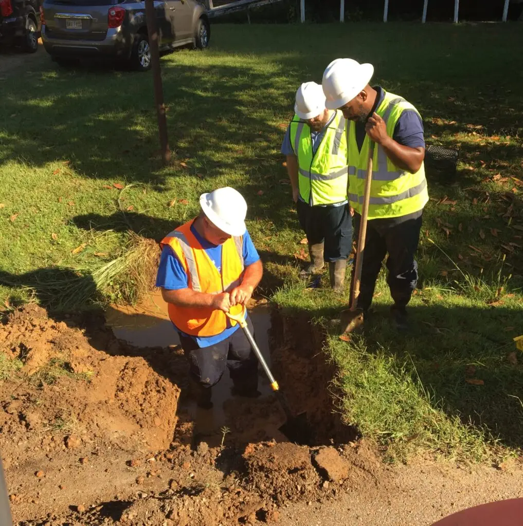 field technicians working on a broken water pipe digging in a yard