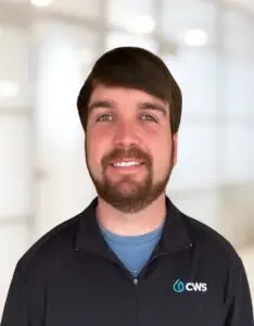 A professional headshot of Joseph Jones wearing a CWS-branded black zip-up jacket.
