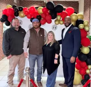 Four people standing in front of a balloon arch