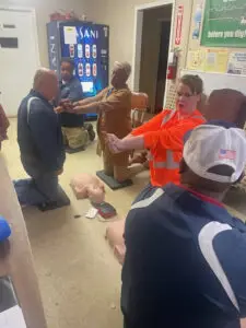 A person instructing a group how to do CPR on dummies