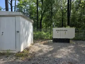 A shed near the forest in a gravel lot