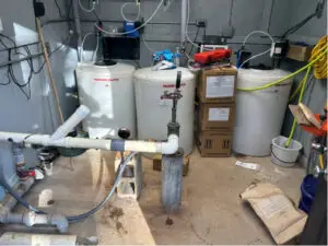 Interior of a water treatment well house featuring chemical solution tanks and a well head.