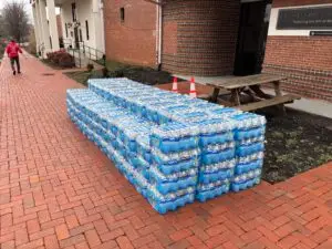 Multiple cases of water on a brick sidewalk
