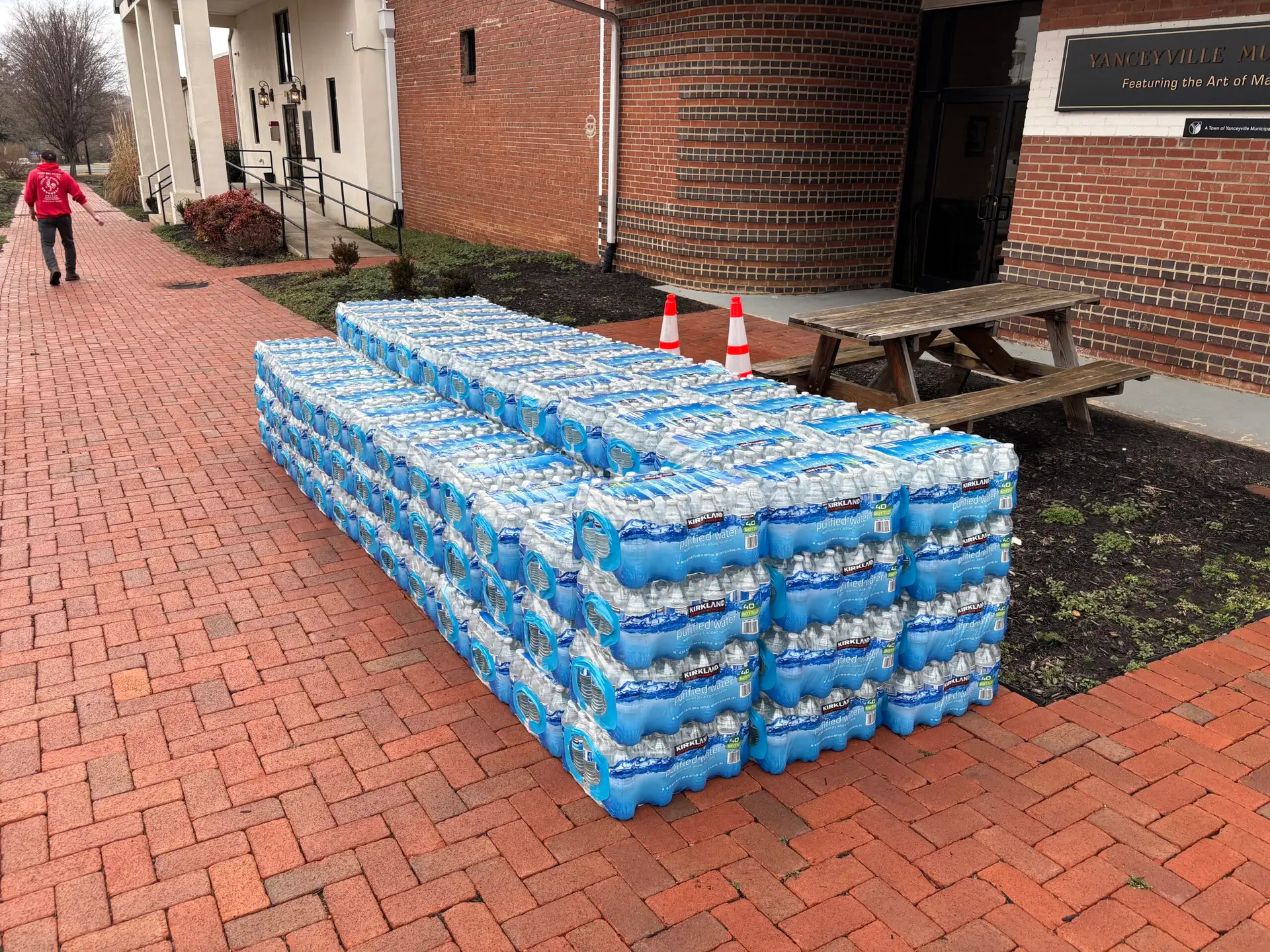 Multiple cases of water on a brick sidewalk