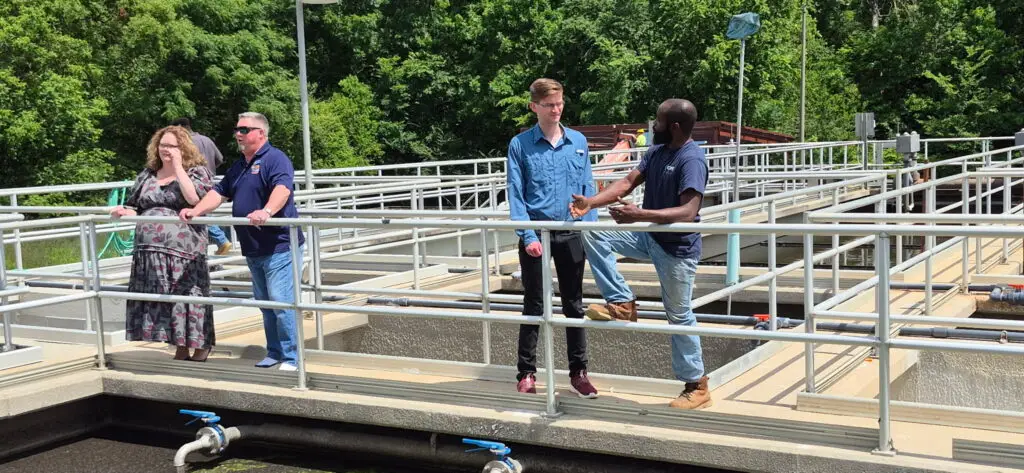 A group of four people leaning on railing of wastewater treatment plant