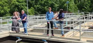 A group of four people leaning on railing of wastewater treatment plant