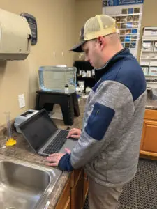 Man standing in a lab working on a laptop