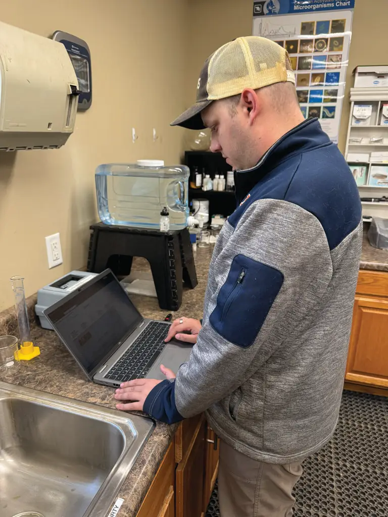 Man standing in a lab working on a laptop